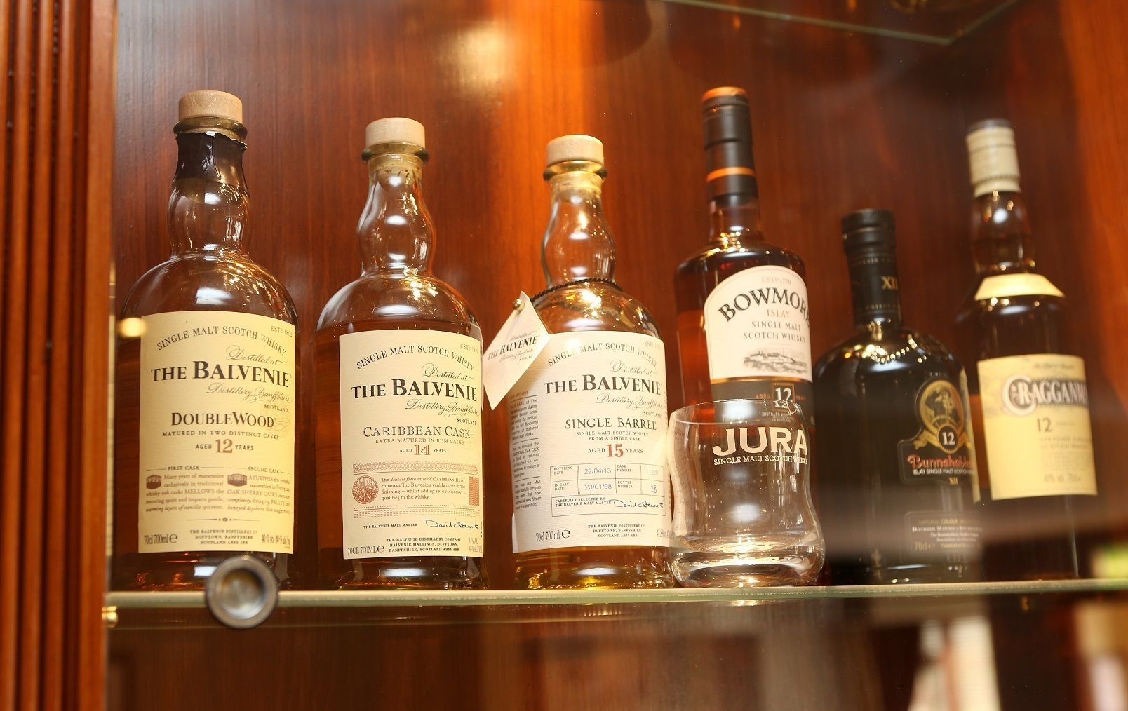 Ein Regal mit verschiedenen Flaschen Single Malt Scotch Whisky, darunter Marken wie The Balvenie, Jura und Bowmore.