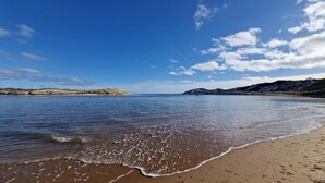Une plage avec des eaux calmes et un ciel dégagé.