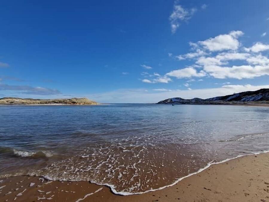 A beach with calm waters and a clear sky.