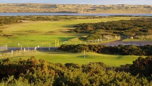 Un parcours de golf avec un plan d’eau en arrière-plan, entouré de verdure et de collines.