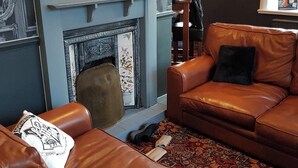 A cozy living room with a fireplace, leather sofas, and a decorative wall with a sign. - Bridge Inn Hotel  by Greene King Inns (Wirral)
