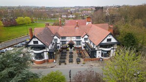 A traditional inn with a central entrance, outdoor seating area, and a parking lot in front. - Bridge Inn Hotel  by Greene King Inns (Wirral)