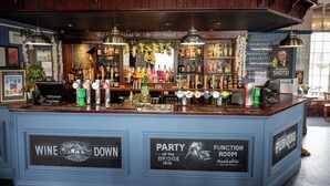 A bar area with a blue counter, multiple beer taps, and a sign for a party room. - Bridge Inn Hotel  by Greene King Inns (Wirral)