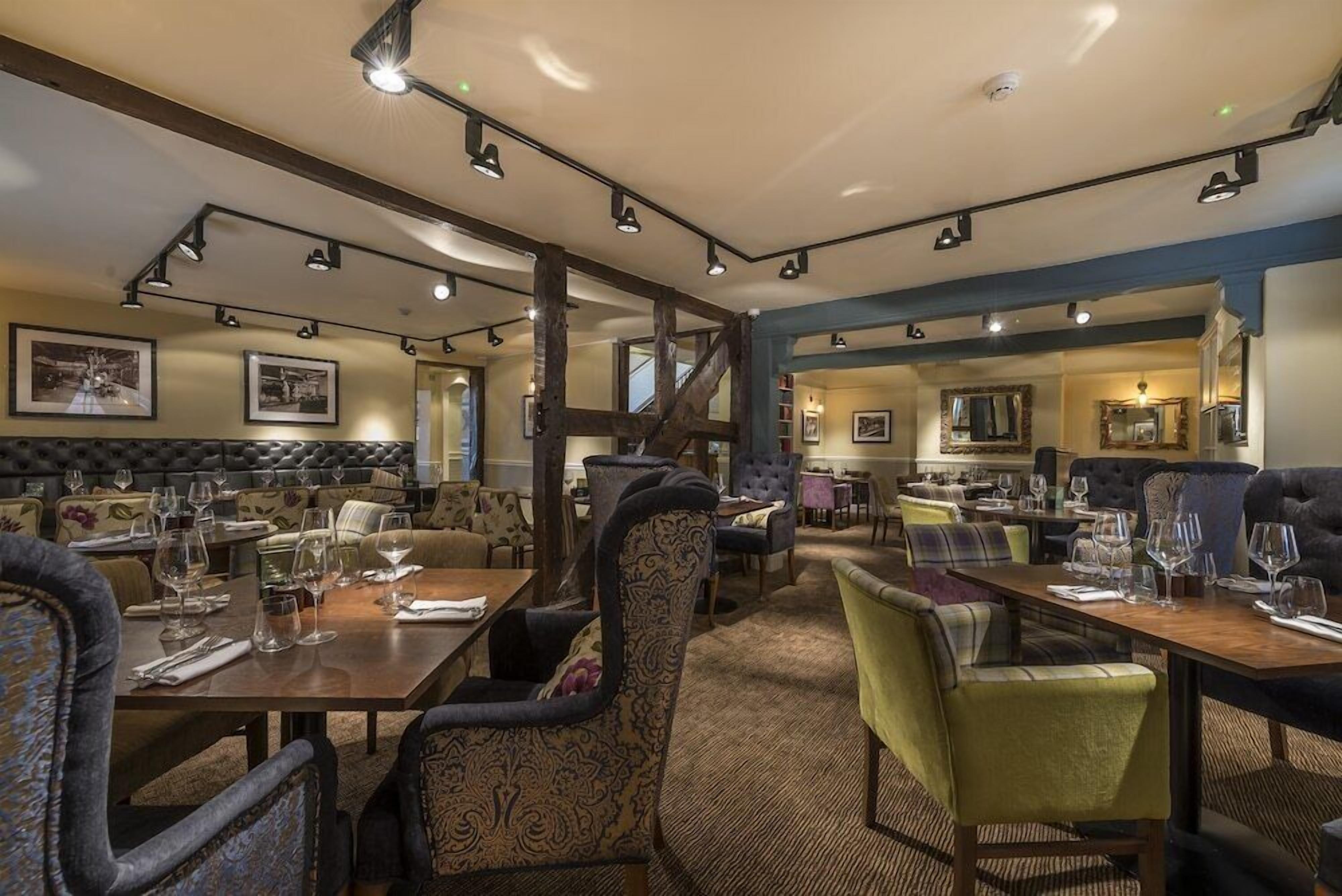 A restaurant with multiple dining areas, including a bar/lounge with high stools and a separate dining section with tables and chairs.