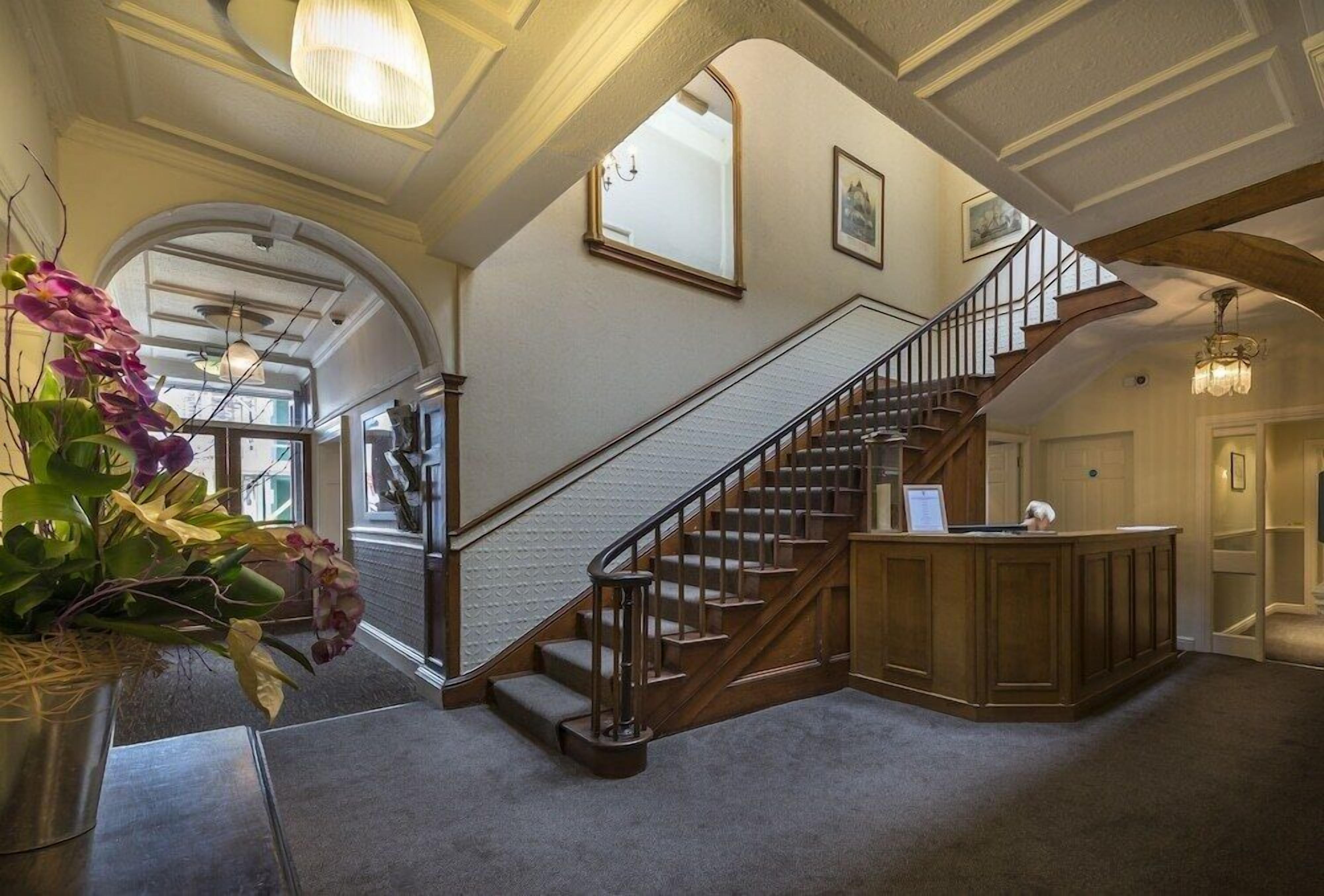 A grand staircase with wooden railings and a reception desk at the bottom.