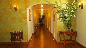 A hallway with wooden flooring, a staircase at the end, and wall-mounted lighting fixtures. - The Firs (Nuwara Eliya)