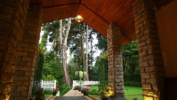 A covered outdoor area with stone pillars, a tiled floor, and potted plants. - The Firs (Nuwara Eliya)