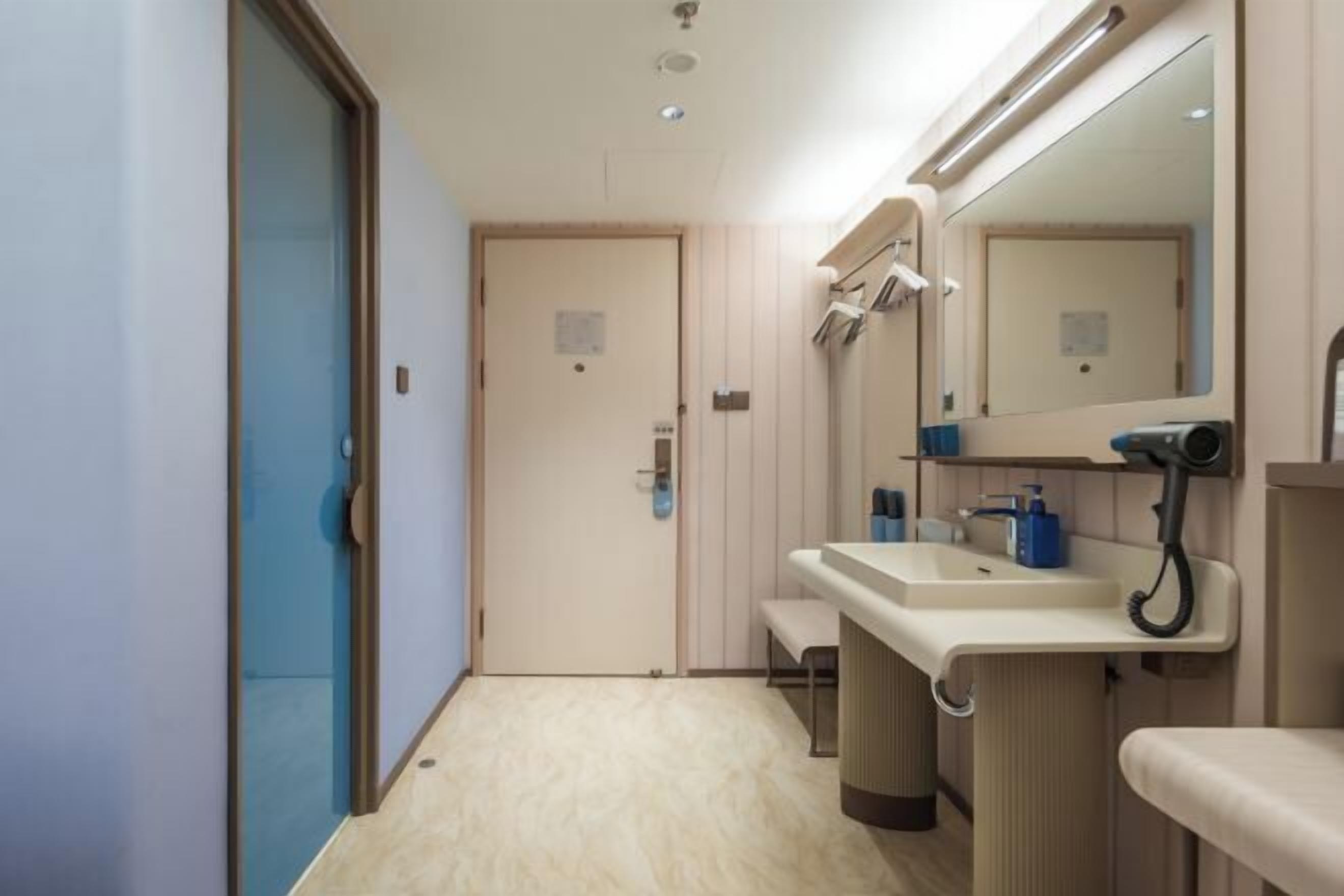 A modern bathroom with a sink, mirror, and bench.