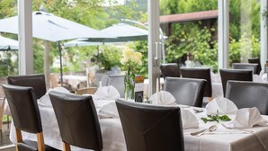 Ein Restaurant mit gedeckten Tischen und Blick auf die grüne Umgebung.