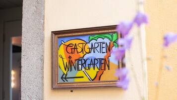 Une enseigne encadrée, affichée sur le mur d’un bâtiment, portant l’inscription « GASTGARTEN WINTERGARTEN ».