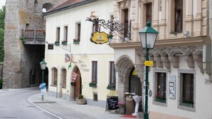 Eine Straße mit historischen Gebäuden, darunter ein Restaurant mit Außenbereich und einem Schild, das auf ein Restaurant hinweist.