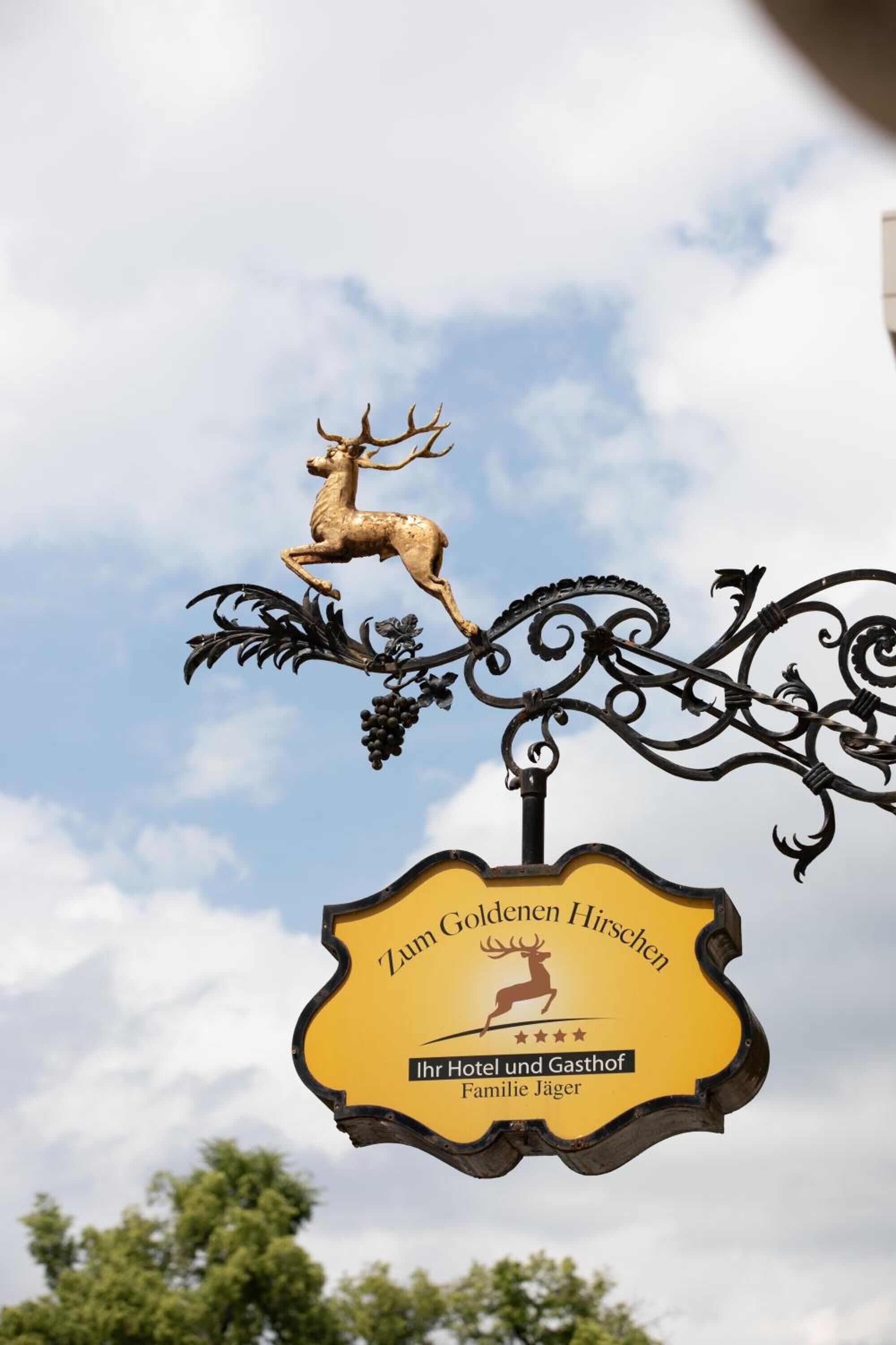 A sign with a deer and grapevine design, indicating a hotel named Zum Goldenen Hirsch.