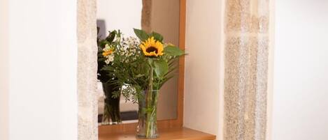 A bedroom with a wooden dresser, a mirror, and a vase with flowers.