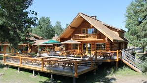 A log cabin with a deck, outdoor seating, and a staircase. - Ten-ee-ah Lodge & Campground (Lac La Hache)