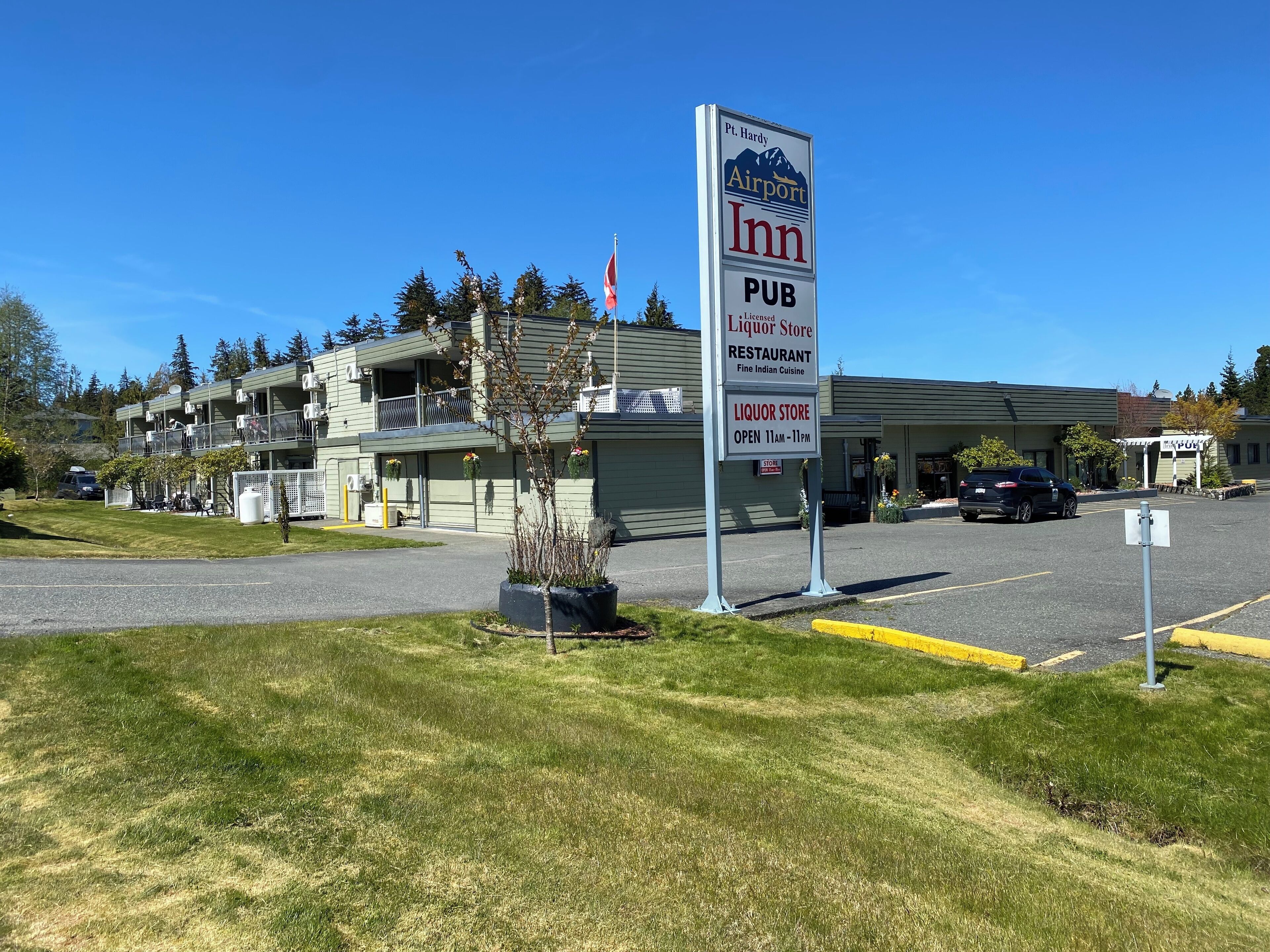 A building with a sign advertising an Inn, Pub, and Liquor Store, offering Fine Indian Cuisine and operating from 11am to 11pm.