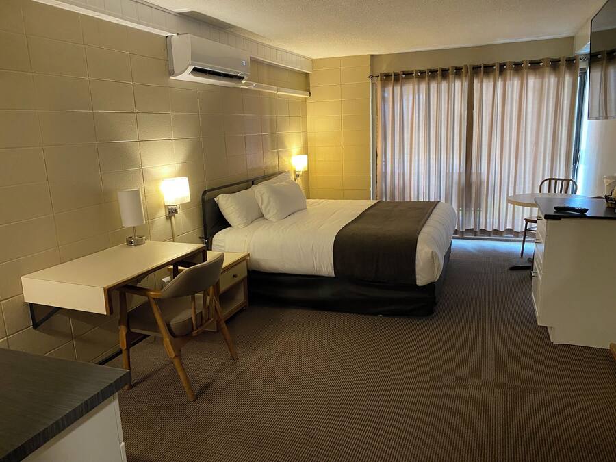 Una habitación de hotel con cama, escritorio, silla y una mesita.