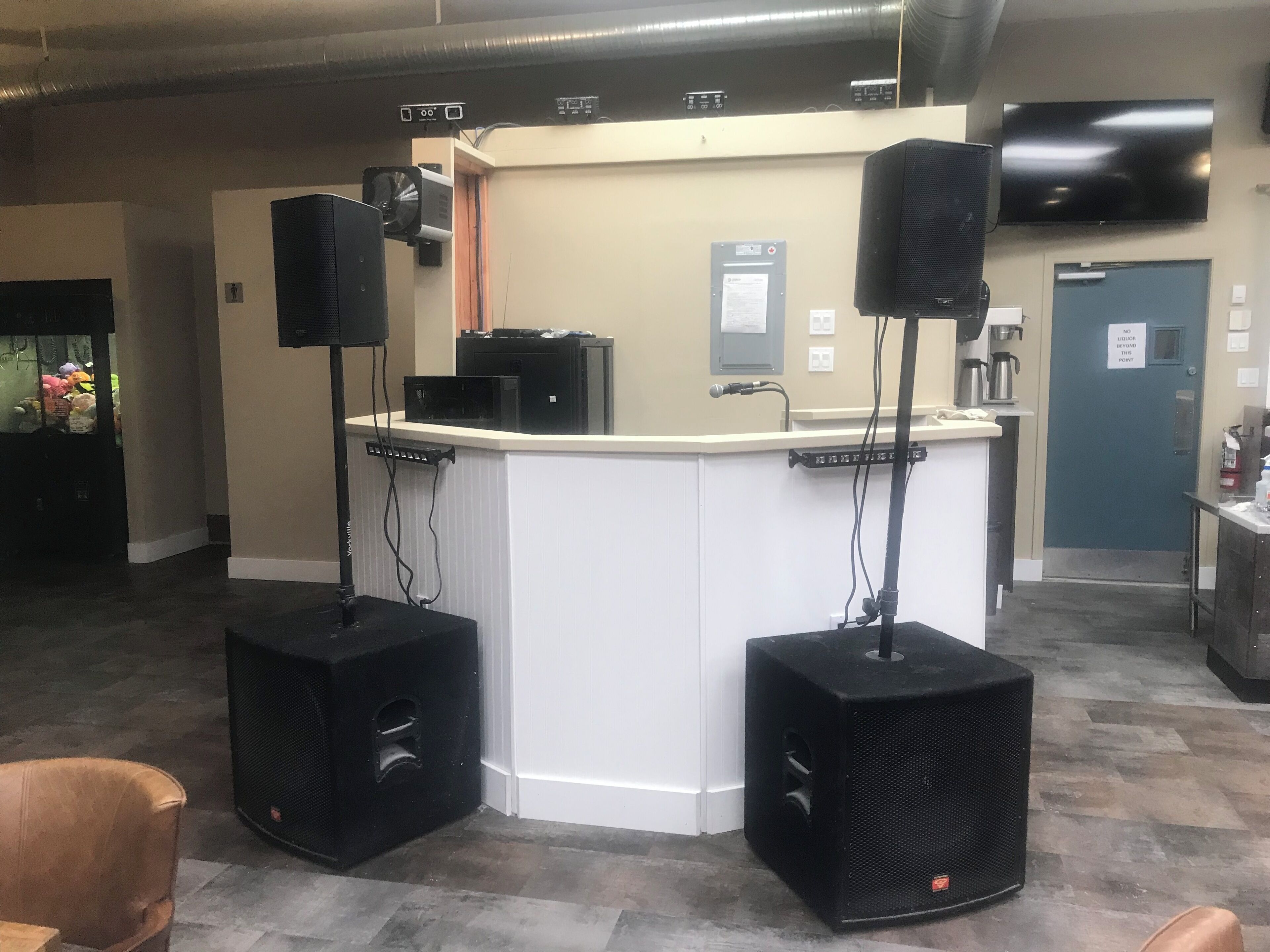 A reception area with a counter, two large speakers, a coffee machine, and a door with a 'No Entry' sign.