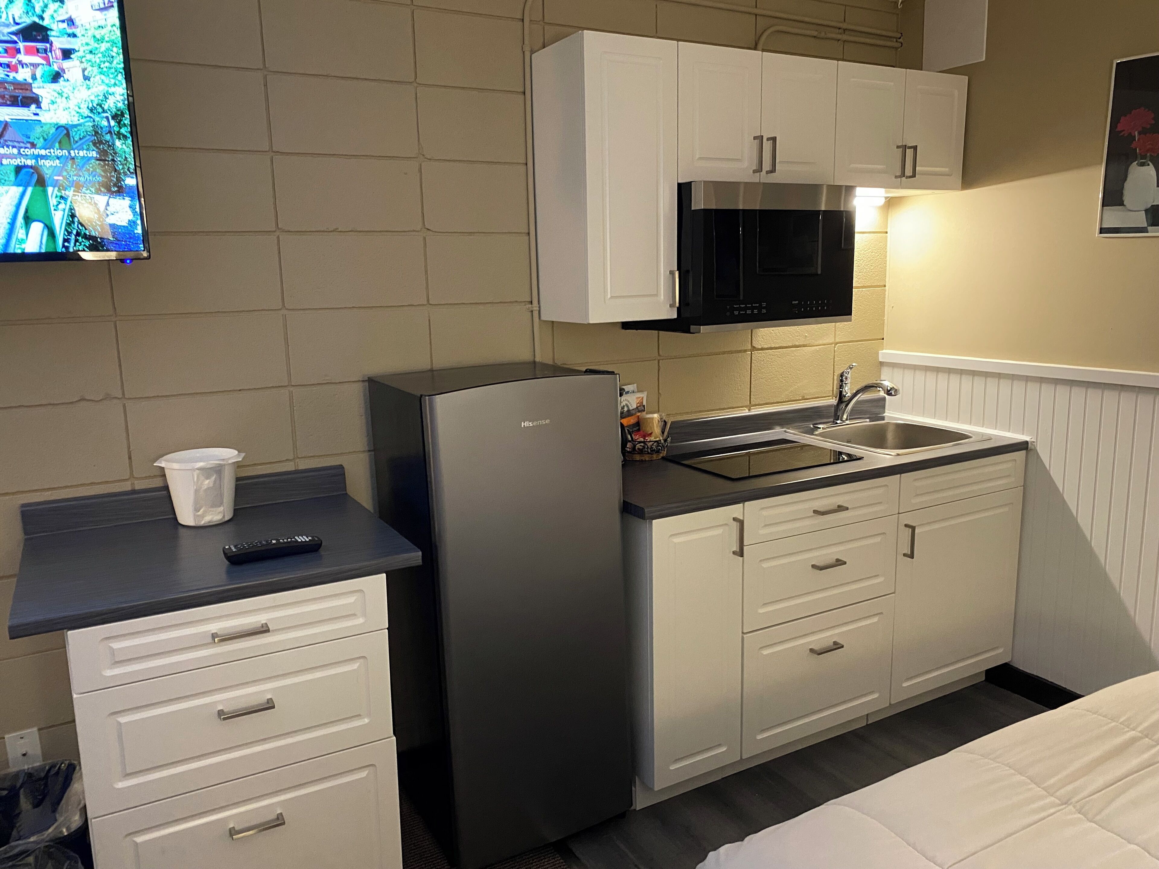 Une petite cuisine équipée comprenant un réfrigérateur, un four à micro-ondes, un évier et un petit plan de travail.