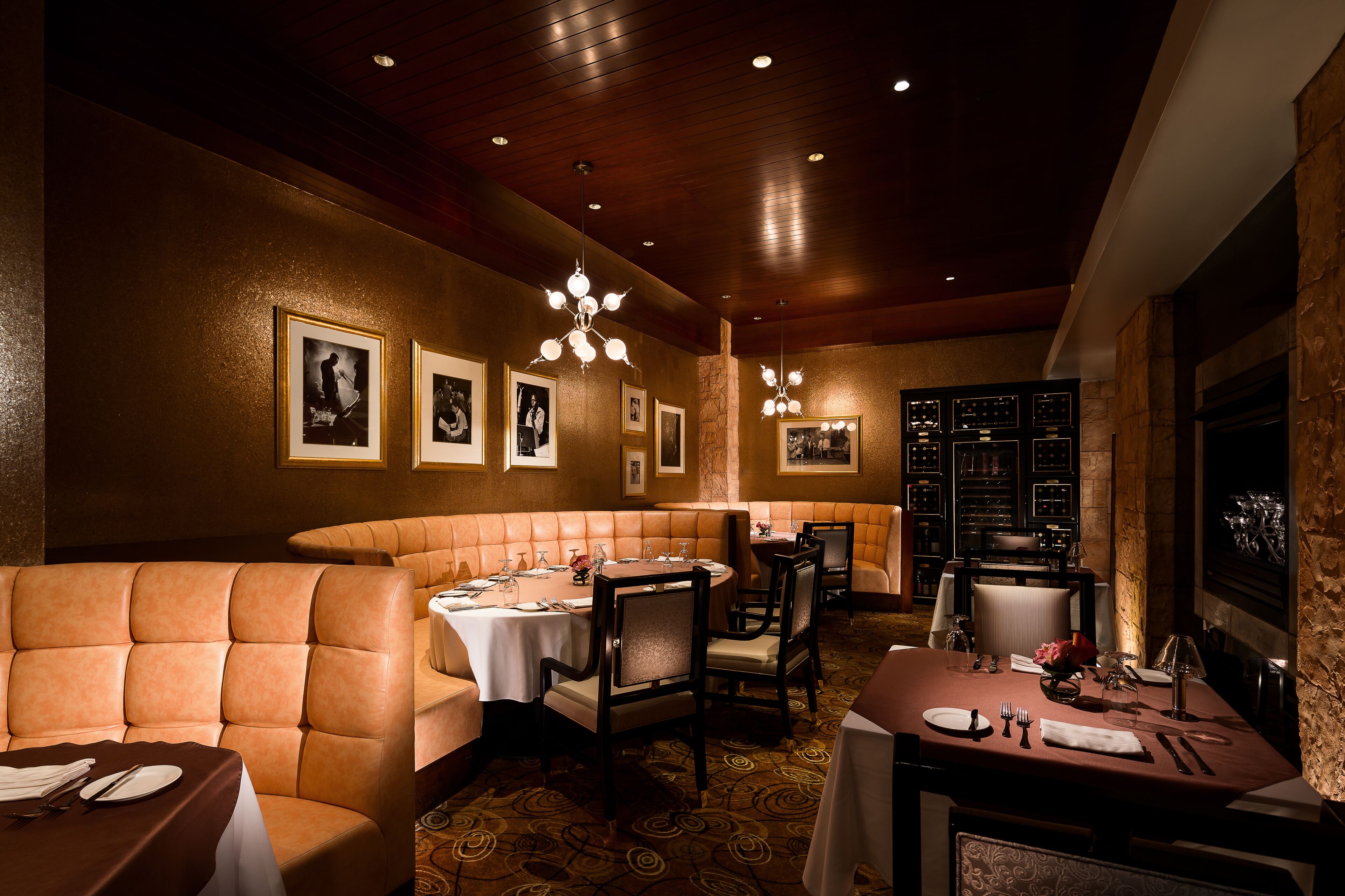 A restaurant with booth seating, tables, and a wine rack.