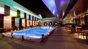 A pool area with seating and tables, surrounded by a modern building with large windows. - Sands Macao (Macau)