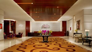 A spacious lobby with a central floral arrangement, a reception desk, and seating areas. - Sands Macao (Macau)