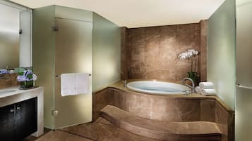 Un baño moderno con ducha de vidrio, bañera independiente y piso de mármol.