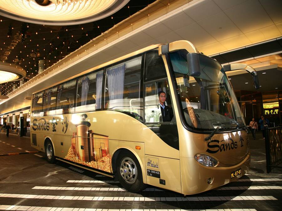 A bus with "Santos" branding parked inside a building with a tiled floor and a curved ceiling with lights.