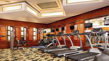 Un gimnasio con cintas de correr, bicicletas estáticas y máquinas de pesas.