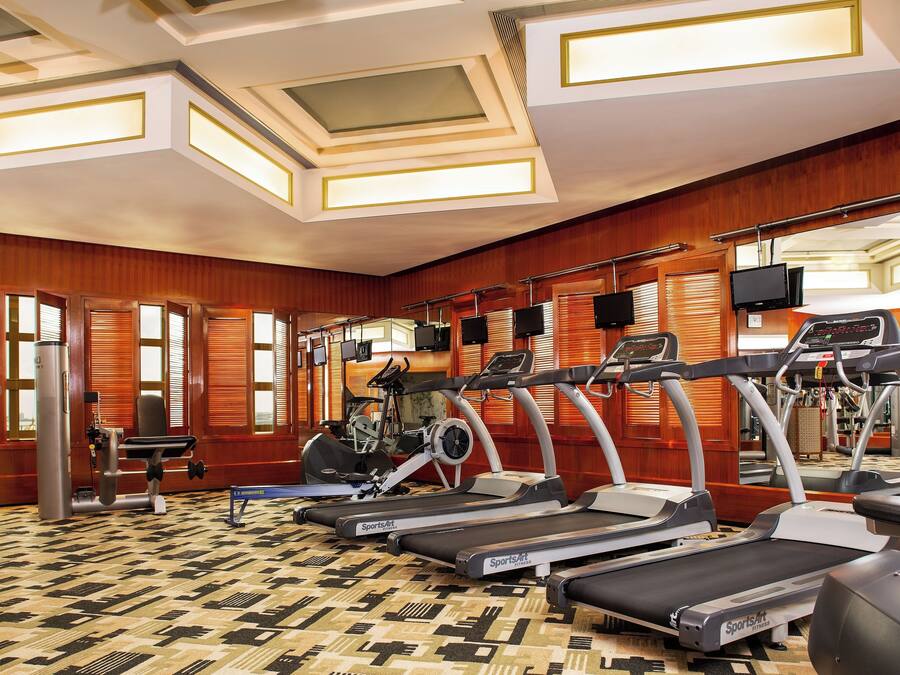 Un gimnasio con cintas de correr, bicicletas estáticas y máquinas de pesas.