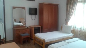 Un dormitorio con cama de madera, armario de madera, escritorio con silla, espejo y televisor en la pared.