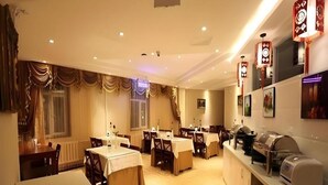 A restaurant with multiple tables and chairs, a counter with a coffee machine, and decorative wall lights.