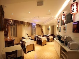 Un restaurante con varias mesas y sillas, una barra con una máquina de café e iluminación decorativa en las paredes.