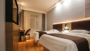 Une chambre d’hôtel avec deux lits, un bureau et une chaise.