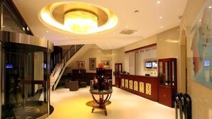 A hotel lobby with a staircase, a reception desk, and a glass table.