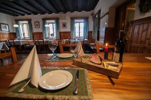 A dining table set with plates, glasses, a knife, a candle, and a bottle of wine, suggesting a meal setting in a restaurant with wooden furniture and a cozy atmosphere.