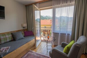 Una habitación con sofá, sillón y una mesita con una botella y vasos.