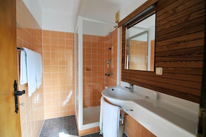 A bathroom with a shower, a sink, and a mirror.