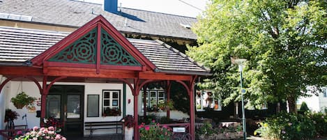 A traditional building with a red and white facade, a pitched roof, and a small porch with a sign that reads 'Kirchewei'.