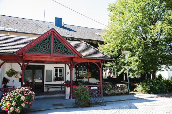 A traditional building with a red and white facade, a pitched roof, and a small porch with a sign that reads 'Kirchewei'.