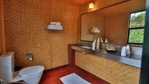 A bathroom with a toilet, a sink with a mirror, and a window. - The Rainforest Ecolodge Sinharaja (Deniyaya)