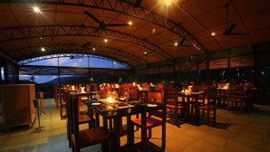 An indoor dining area with tables and chairs, ceiling fans, and a view of the outdoors. - The Rainforest Ecolodge Sinharaja (Deniyaya)