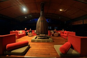 A lounge area with red sofas and a central fire feature. - The Rainforest Ecolodge Sinharaja (Deniyaya)