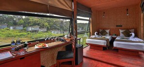 A room with two beds, a desk with a laptop, a telephone, and a view of greenery outside. - The Rainforest Ecolodge Sinharaja (Deniyaya)