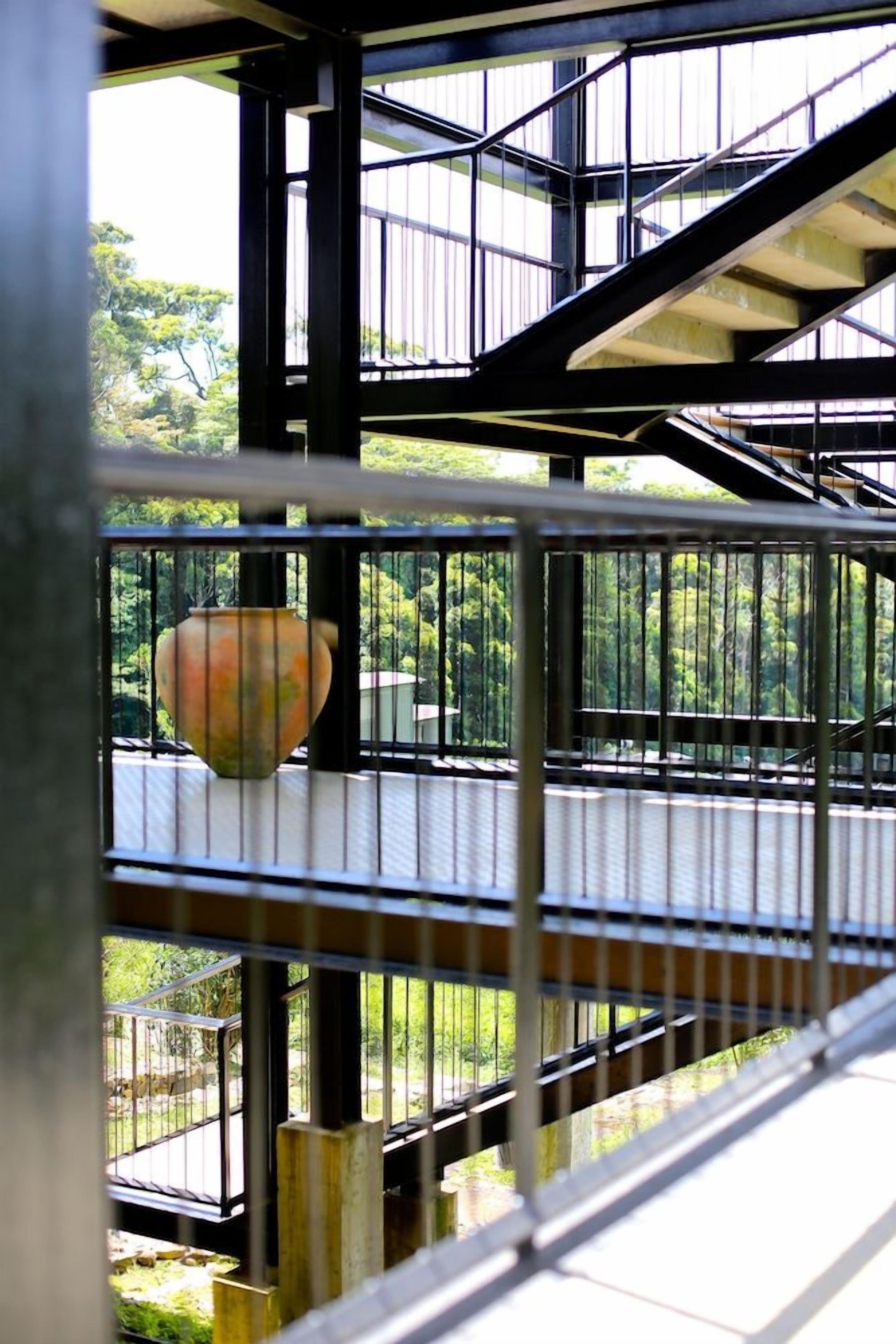 A metal staircase with a railing, leading to an outdoor area with greenery.