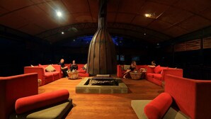 A lounge area with red sofas, a central fire feature, and a high ceiling. - The Rainforest Ecolodge Sinharaja (Deniyaya)