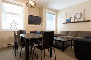 Una sala de estar moderna con chimenea, un televisor de pantalla plana, una mesa de comedor con sillas, un sofá y una mesa de centro.