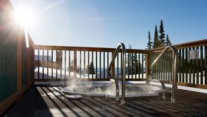 A hot tub on a wooden deck with a view of snow-covered mountains and evergreen trees. - Vance Creek Hotel & Conference Centre (Silver Star Mountain)