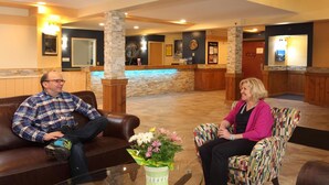 A lobby with a reception desk, a stone pillar, and a patterned armchair. - Vance Creek Hotel & Conference Centre (Silver Star Mountain)