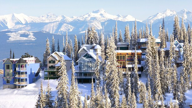 A snow-covered mountain resort with multiple buildings, including a large lodge and several smaller cabins, surrounded by tall evergreen trees. - Vance Creek Hotel & Conference Centre (Silver Star Mountain)