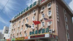 A multi-story hotel with a red awning and several flags, including an American flag. - Green Tree Inn Express (Weihai)